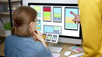 Colleagues web designers are working on the development of an application interface for a mobile phone on a computer screen. user experience.