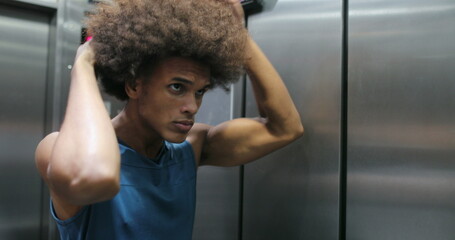 African man examining himself in front of elevator mirror