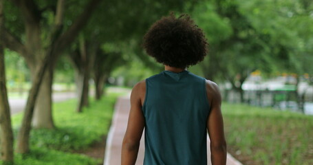 Back of african black man walking in nature pathway park