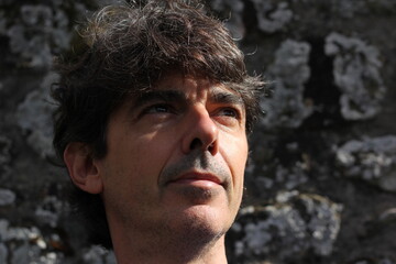 Portrait of an Italian man with dark hair against a medieval wall