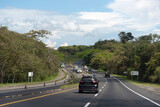 Fototapeta Sawanna - Cars on a highway between tropical forest in Colombia.
