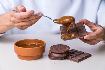 woman's hands putting dulce de leche on a chocolate, not suitable for diabetics.