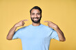 Happy indian man pointing fingers at healthy white teeth advertising dentist services or dental care product commercial promo, presenting perfect smile standing isolated on yellow background.