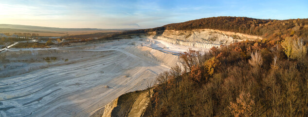 Wall Mural - Aerial view of open pit mine of sandstone materials for construction industry with excavators and dump trucks. Heavy equipment in mining and production of useful minerals concept