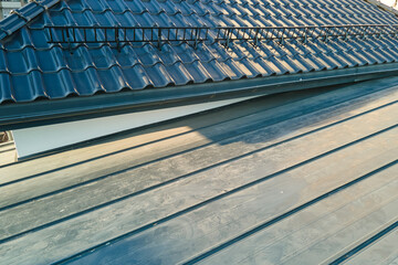 Wall Mural - Closeup snow guard for safety in winter on house roof top covered with ceramic shingles. Tiled covering of building