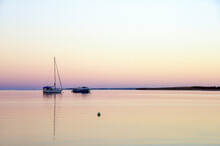 Calm Waters For A Fishing Boat In The Early Morning Hours Against A Pastel Skyline.