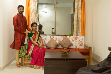 Hindu marathi young couple smiling in Indian traditional festival clothes in their new home. Home loan, health insurance, house warming party, family, love, anniversary, cuddle