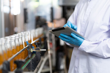 Manufacturer checking product bottles fruit juice on the conveyor belt in the beverage factory. Worker checks product bottles in beverage factory. Inspection quality control