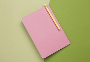 Wall Mural - Cover of a pink notepad with pen on green background