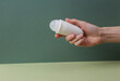 Hand holds antiperspirant roller stick on green background. Beauty concept.