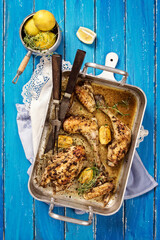 Wall Mural - Traditional French poulet au citron with chicken wings and drumsticks in white wine lemon sauce served as top view in a braising pan