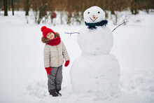 Adorable Preschooler Girl Building A Snowman On A Day With Heavy Snowfall
