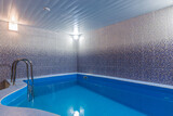 Fototapeta Paryż - he blue pool in the wellness center with shiny mosaic tiles on the walls.