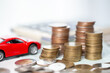 Car toy vehicle with stack coin money on background. Planning to manage transportation finance costs. Concept of car insurance business, saving buy - sale with tax and loan for new car.