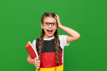 Education in Germany for children. A little girl with a German flag and notebooks on a green isolated background. Learning foreign languages.