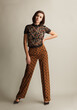 © Sergey Chumakov - fashionable woman in vintage style dotted brown pants and lace floral shirt, bob hairstyle on studio background