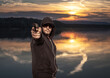 © bogdan vacarciuc - A man with a hood and sunglasses prepares to shoot the gun. The man was shooting with the gun on the shore of the lake, at sunset.