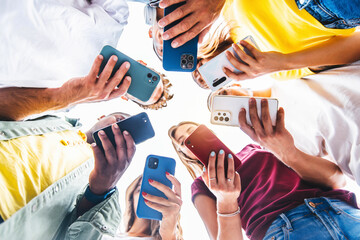 teens in circle holding smart mobile phones - multicultural young people using cellphones outside - 