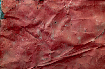 Old crumpled metal sheet, faded red paint covered with dust and dirt, grungy textured surface, closeup vintage background