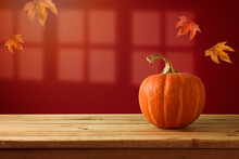 Autumn Pumpkin On Wooden  Table Over Trendy Red Wall Background With Window Shadow.  Halloween Or Thanksgiving Holiday Mock Up For Design And Product Display.