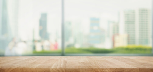 Wall Mural - Selective focus.Top of wood  table with window glass and cityscape background.