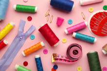 Sewing Supplies On Pink Background: Sewing Thread, Scissors, A Large Spool Of Thread, Pieces Of Cloth, Needles,centimeter, Buttons