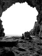 Black and white photo of a cave carved into the cliff by Sandyhills Beach.