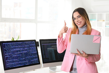 Canvas Print - Transgender programmer with laptop showing thumb-up in office