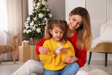 Canvas Print - Happy mother and daughter making paper snowflake near Christmas tree at home