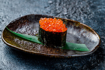 Wall Mural - sushi Gunkan with red caviar on dark stone table