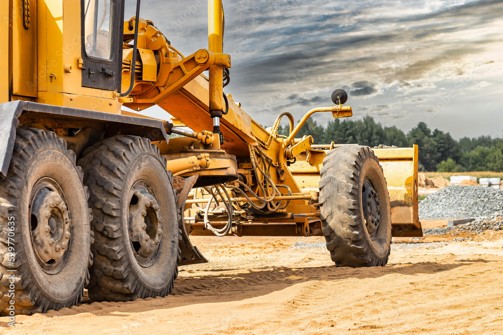Road grader at the construction site. Powerful construction machine for ...