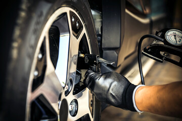 Auto mechanic checking air pressure and inflating car tires. Concept of car care service and maintenance or fix the car leaky or flat tire.