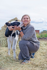 Wall Mural - pretty black-white new born calf posing with farmer.