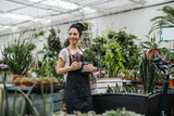 Fototapeta  - Shot of a young woman working with plants in a garden centre