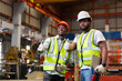 © eakgrungenerd - Two man African American engineer workers giving thumbs up standing work success in manufacturing factory workplace. happy man engineering at industrial.