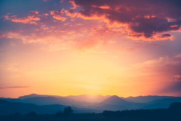 Wall Mural - spectacular sunrise over mountain range under mist in the morning light. colorful clouds in orange s