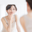 © lielos - 鏡を見ながらスキンケアをする日本人女性