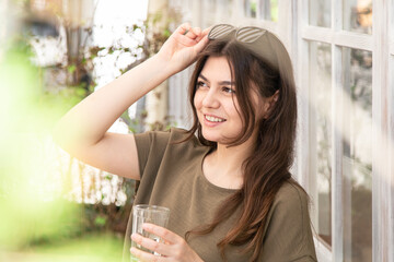  Attractive young woman with a glass of water on a summer day on a cafe terrace.
