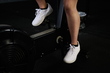 Wall Mural - Close up of woman peddling stationary bike erg