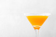Yellow alcoholic cocktail with fruit juice served in martini glass decorated with sugar border. Copy space