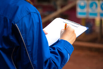 Wall Mural - A safety supervisor or manager is writing down on paper for taking note during safety audit at the operation work site. Industrial safety working action scene, close-up and selective focus.
