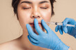 © ME Image - Closeup face young asian woman is getting her lip filler by a beautician with a syringe in hands. Cosmetic rejuvenating facial treatment concept. Aesthetic medical.