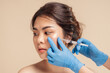© ME Image - Closeup face young asian woman is getting filler under her eye for anti age wrinkle by a beautician with a syringe in hands. Cosmetic rejuvenating facial treatment concept. Aesthetic medical.