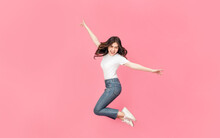 Young Asian Woman In A White T-shirt Jumping Off With Her Arm Raised In Air, A Cheerful Expression On Her Face As She Is Very Happy Over Something Excited Smile In Isolated Pink Background.