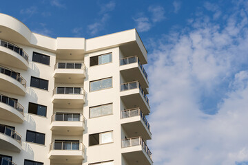 Sticker - Exterior of a modern apartment building against a blue sky with clouds.