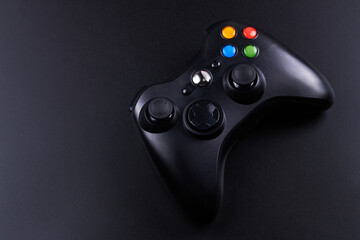 Black video game controller, joystick for game console isolated on black background. Gamer control device close-up