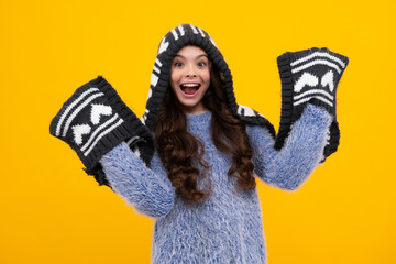 Amazed teenager. Warm hat with hood and scarf. Modern teen girl wearing sweater and knitted hat on isolated yellow background. Excited teen girl.