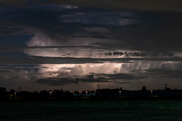 Wall Mural - A Cumulonimbus storm cloud is lit up by lightning at night