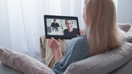 Wall Mural - Online meeting. Casual woman. Video call. Relaxed lady sitting cozy sofa having virtual conference on tablet computer in light room interior.