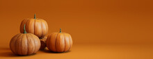 Three Pumpkins On A Orange Colored Background. Autumn Themed Banner With Copy-space.